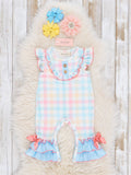 Pastel plaid romper with ruffles on a textured surface